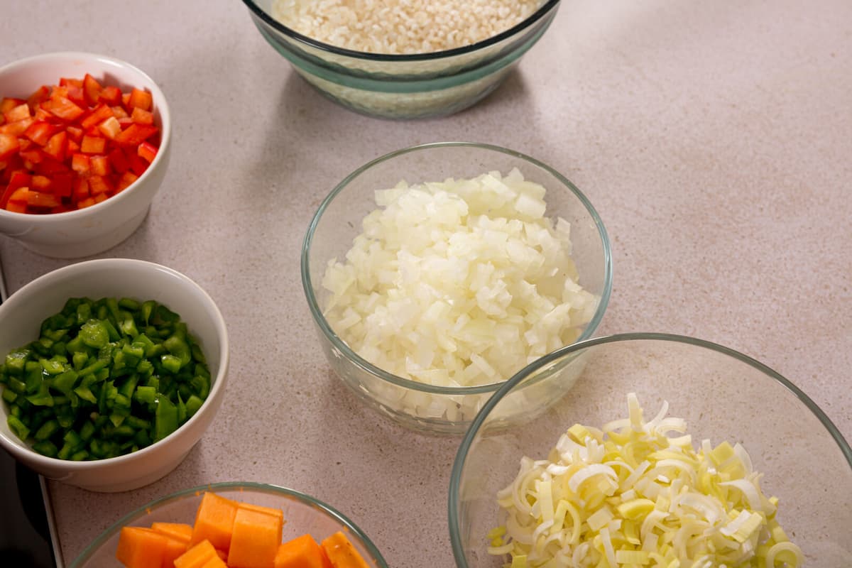 Receta arroz caldoso de verduras paso 1 cortar en brunoise todo lo que vas a necesitar para el sofrito: la cebolla, el puerro, el pimiento rojo y el verde