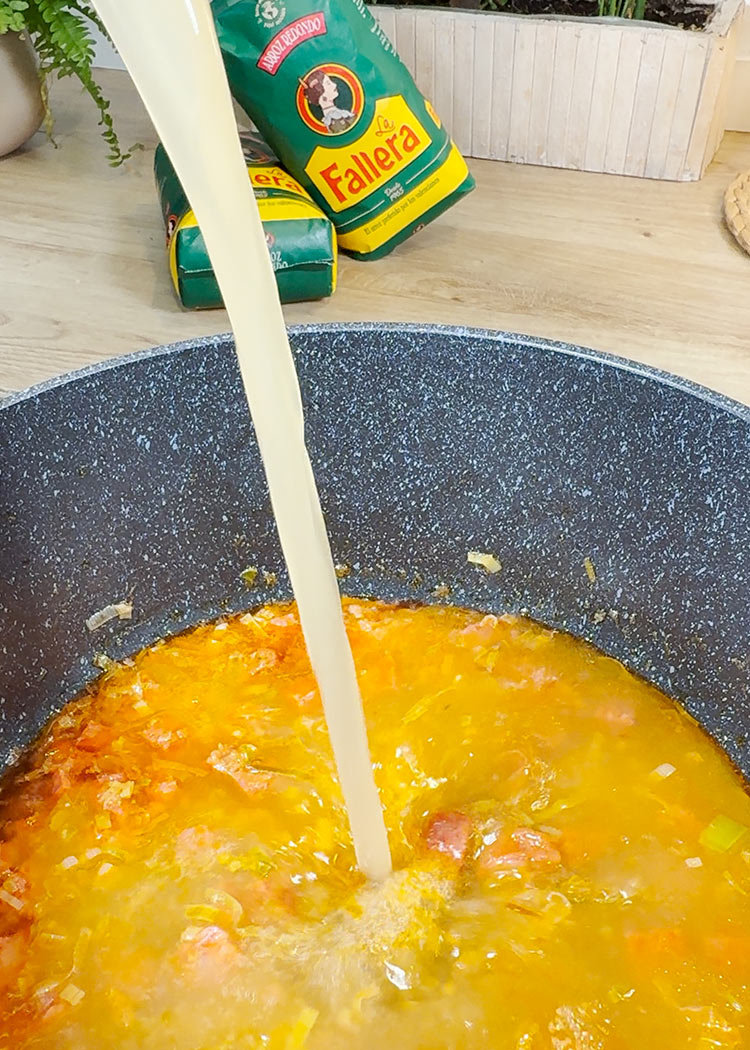 Incorporar caldo a Garbanzos de bote con arroz y chorizo