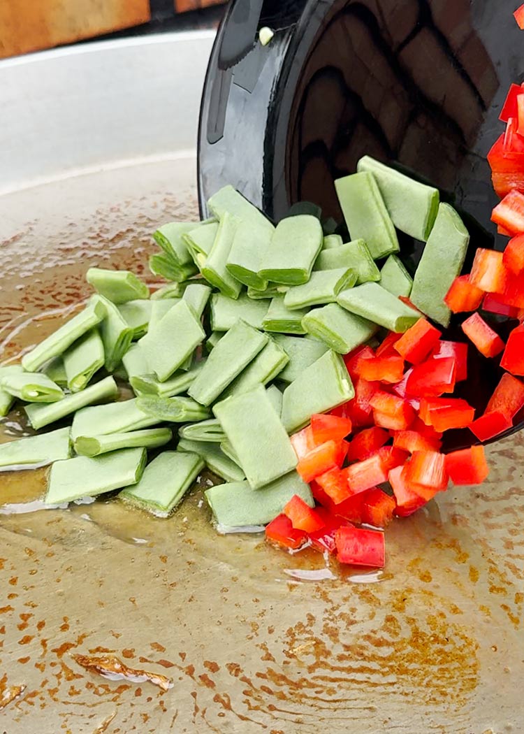 Incorporar habas y pimiento a arroz con muslitos de pollo