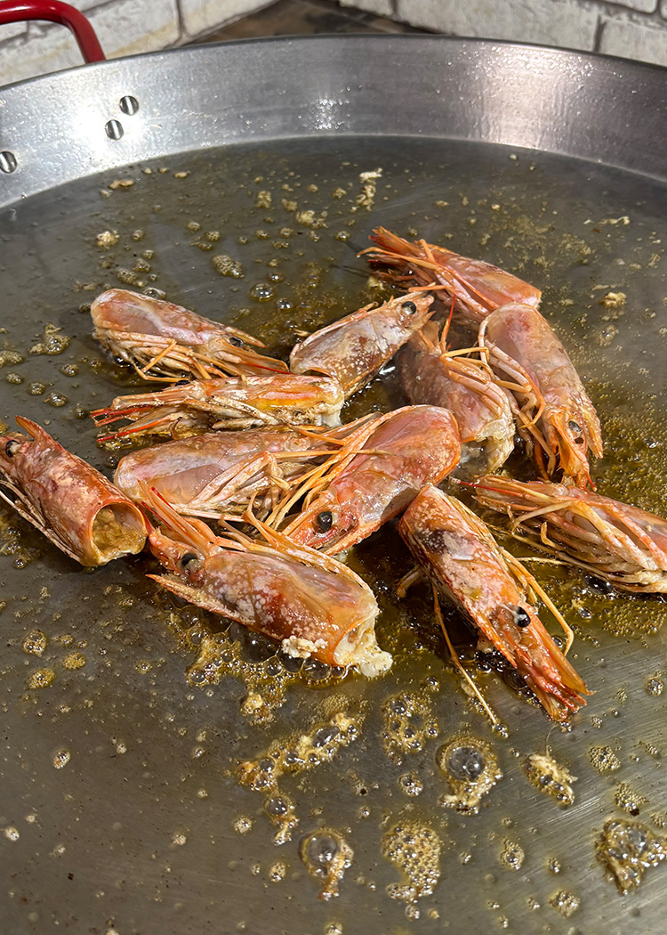 sofríe las cabezas para paella de gambas