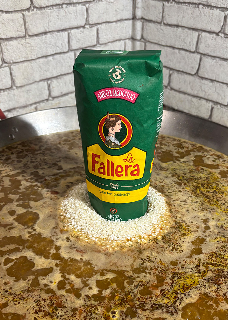 Añadir caldo y arroz para paella de gambas